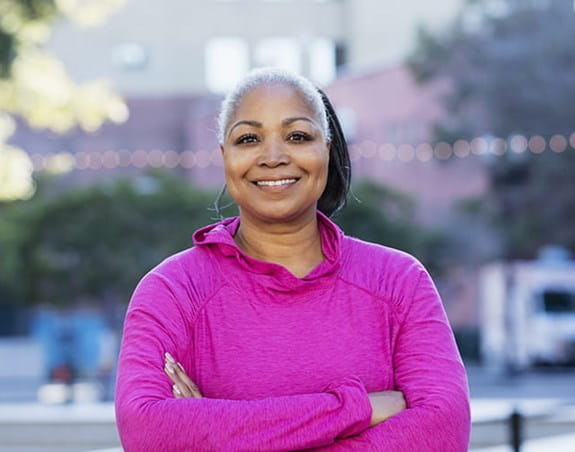 A woman wearing a pink long-sleeve shirt smiling at the camera 