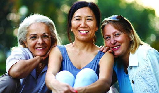 Three female friends sitting together and smiling