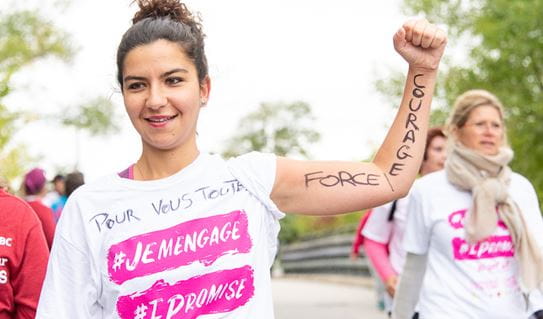 A young woman wearing a CIBC Run for the Cure t-shirt with her fist up in the air 