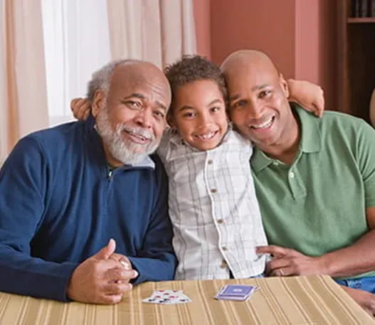 Un jeune garçon assis entre son grand-père et son père, et tous sourient