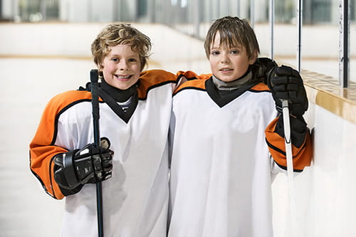Deux jeunes joueurs de hockey souriant et s’étreignant