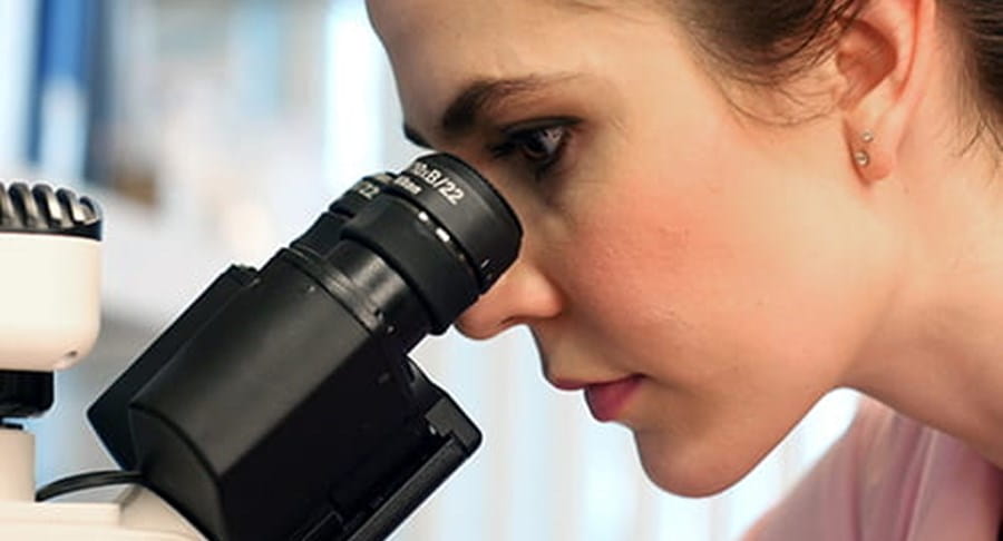Une chercheuse qui regarde à travers un microscope