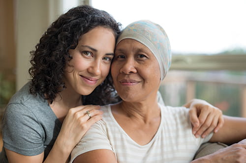 A daughter sitting behind her mother with her arms on her shoulders