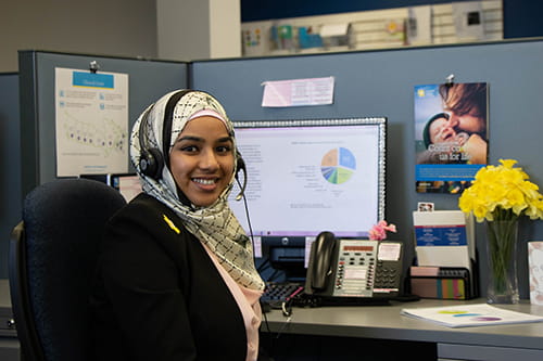 A Cancer Information Specialist with a headset on and sitting at her desk