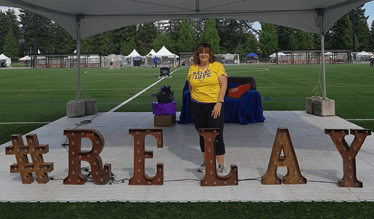 Lianne Wilson standing behind a sign that says Relay.