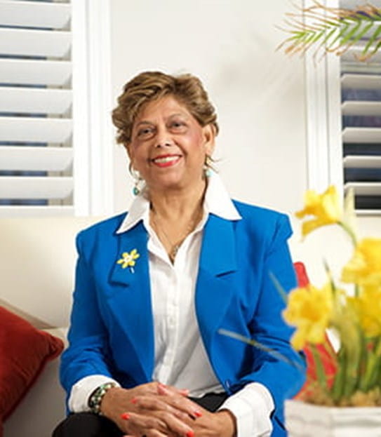 Yaslyma wearing a daffodil pin and sitting next to a bouquet of daffodils