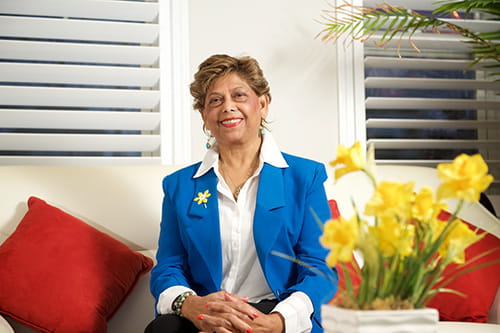Yaslyma wearing a daffodil pin and sitting next to a bouquet of daffodils