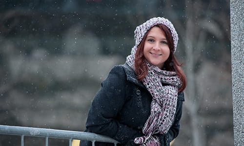 Sarah Midea, Cancer Survivor, leaning against an outdoor railing