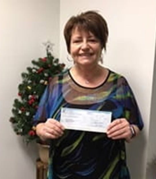Cindy holding up a cheque of her money prize