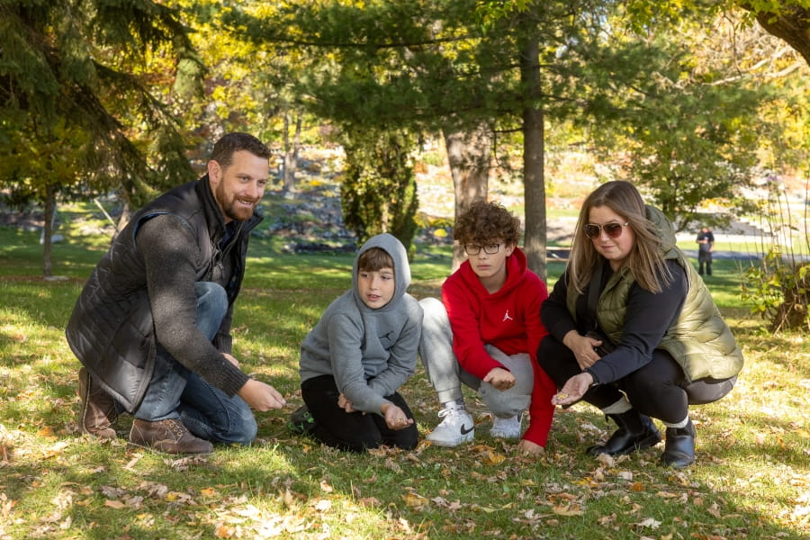 Tyler et sa famille assis dans l’herbe sous les arbres.