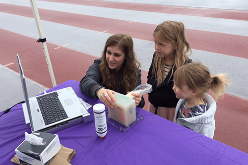 Jessica, Scientist, looking at a computer with two young children
