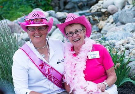 Eleanor Rudd and a participant of Golf for the Cure stand beside each other in bright pink costumes