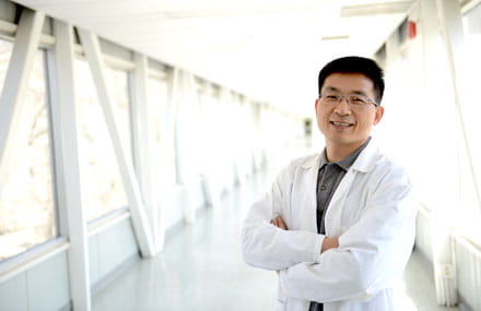 Dr. Shawn Li stands with his arms crossed in a hallway