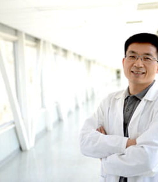 Le Dr Shawn Li, les bras croisés, dans un corridor.