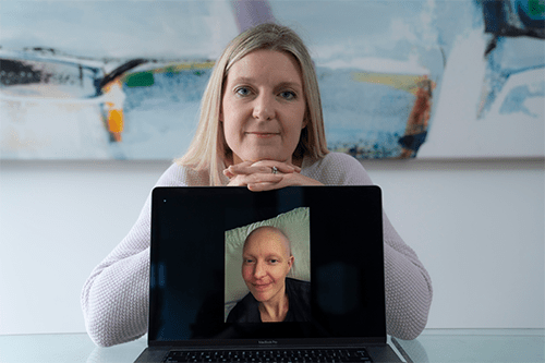 Kathy holding a picture of herself during her cancer treatment