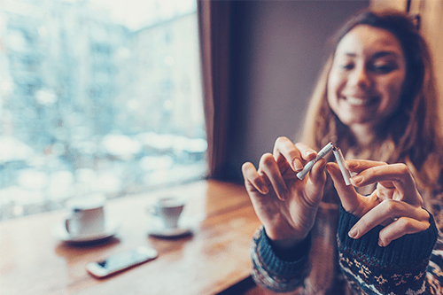 A young woman breaks a cigarette in half