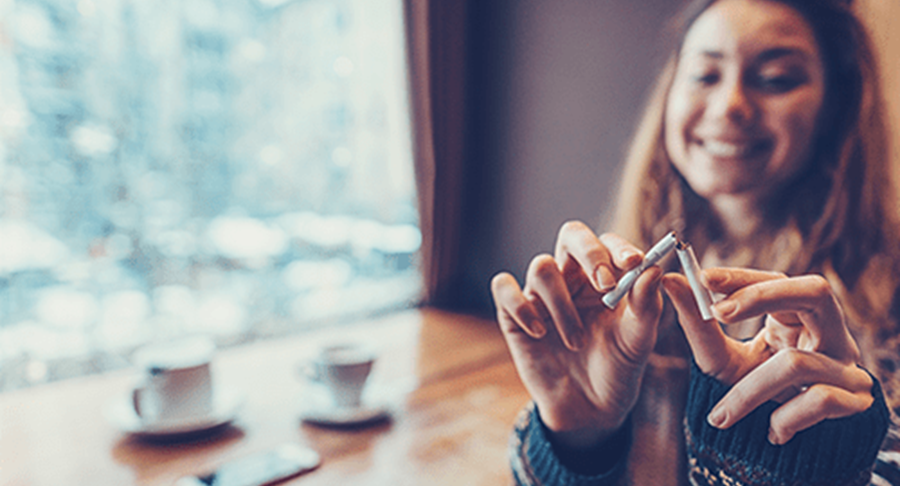 A young woman breaks a cigarette in half