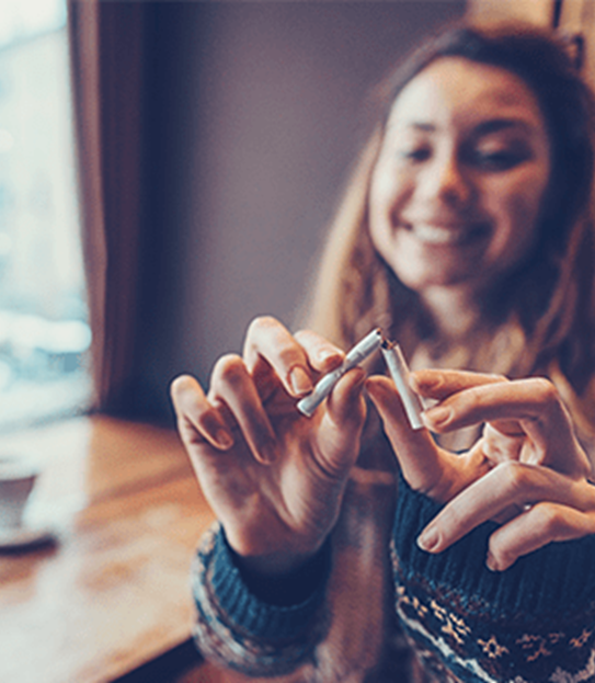 A young woman breaks a cigarette in half