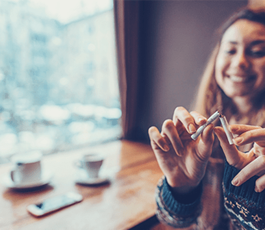 A young woman breaks a cigarette in half