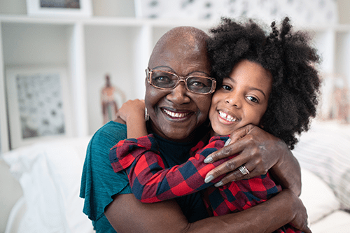 A grandmother hugging her granddaughter.