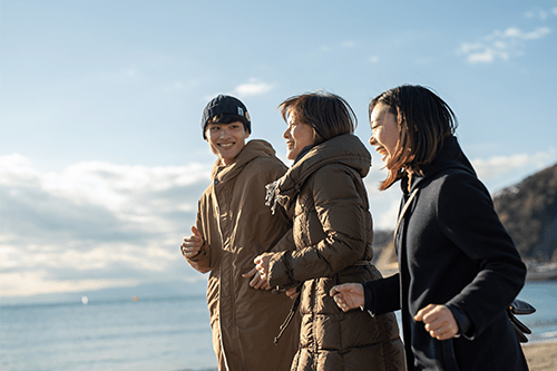 A grandmother, mother and son jogging on the beach in winter.