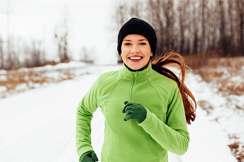 A woman running on a trail in the winter.