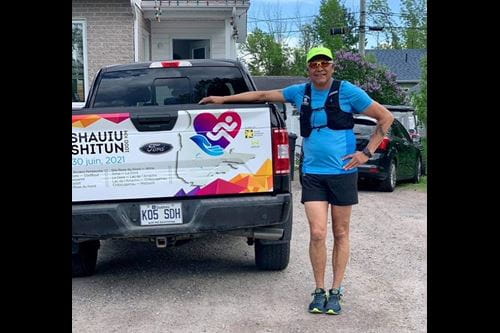 A man wearing a running outfit standing beside a truck.