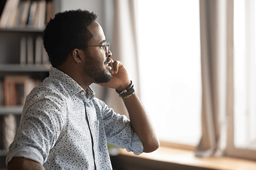 Un homme qui parle au téléphone en regardant par la fenêtre.