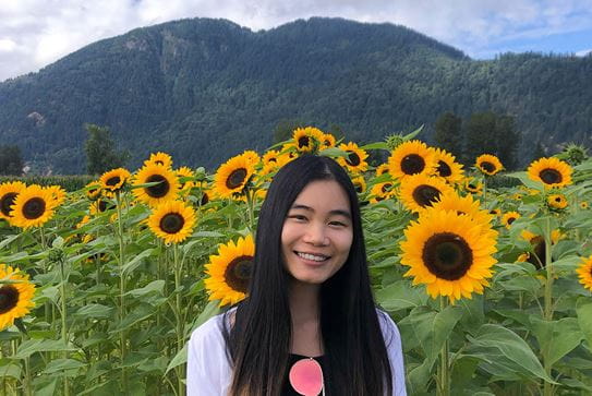 Rachel, a Canadian Cancer Society volunteer, standing in a field of sunflowers.