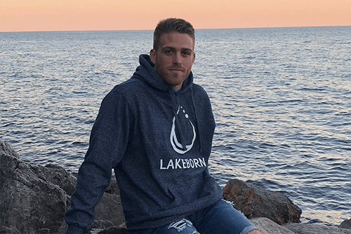 Luke sitting on a rock in front of the water.