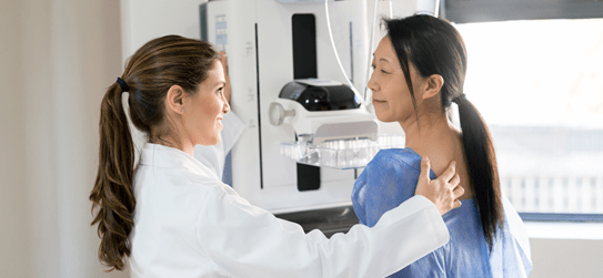 Woman getting a breast screening from a female doctor.