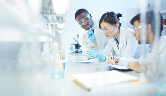 Three researchers conducting a test with test tubes and writing notes.