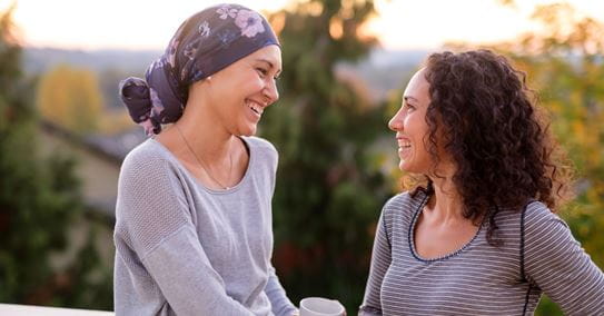 Two women talking and laughing. One woman is wearing a head scarf.
