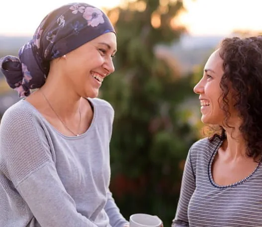 Two women talking and laughing. One woman is wearing a head scarf.