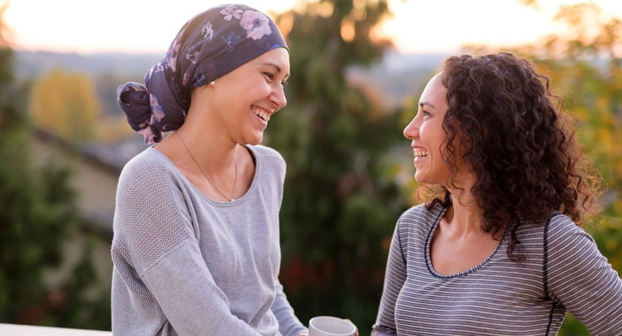 Two women talking and laughing. One woman is wearing a head scarf.