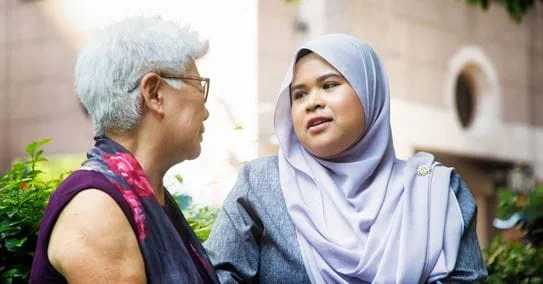 Woman with short grey hair taking to younger woman.