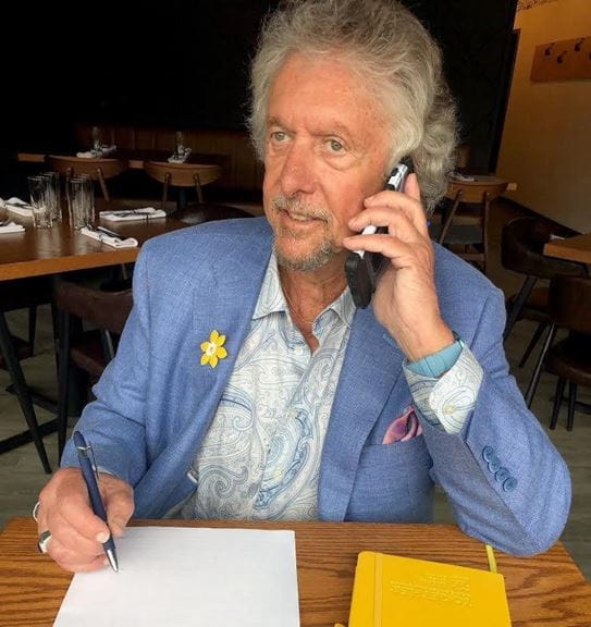 Al Shell talking on a cell phone, while writing on a piece of paper.