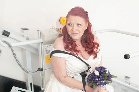 Debra sitting in a hospital room, wearing a white dress.