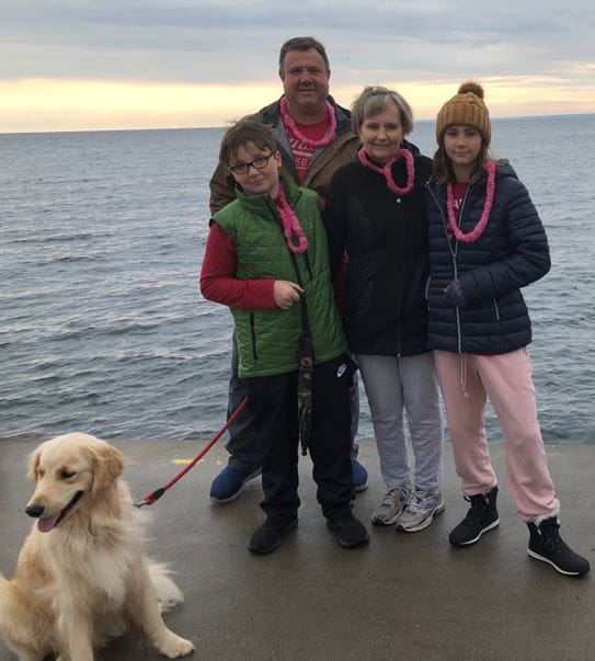 Konstance, standing with her family and dog on a pier.