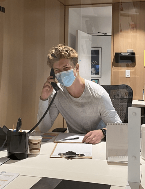 Owen, sitting at the lodge front desk, answering a phone call.