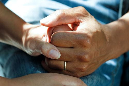 Two people holding hands on a hospital bed.