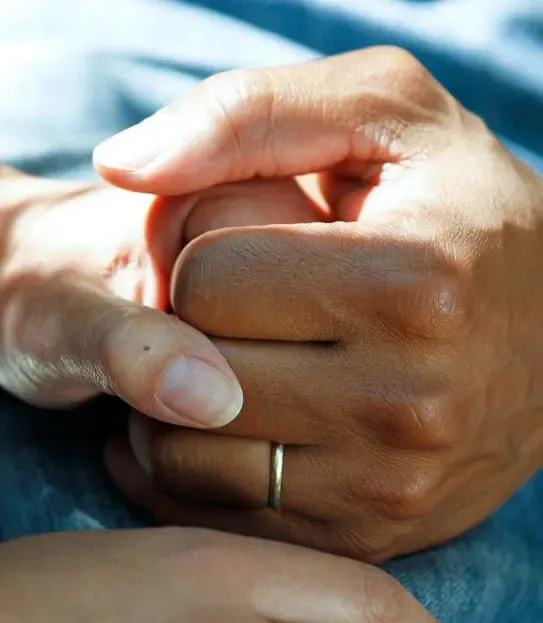 Two people holding hands on a hospital bed.