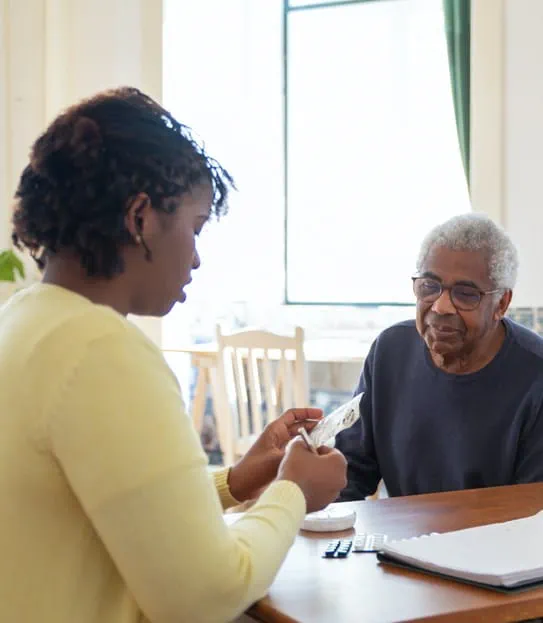 A younger person reviewing medications with an older person.