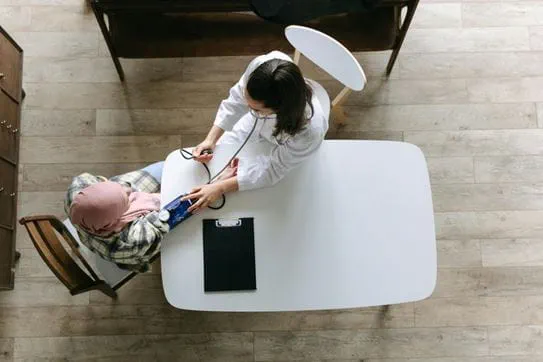 A doctor taking the blood pressure of a person with cancer at a table