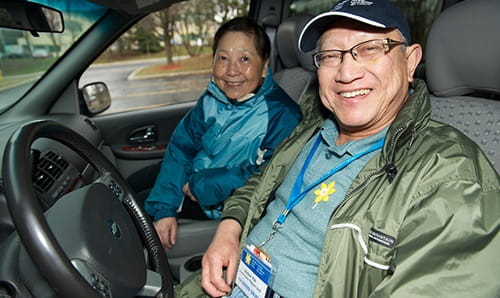 Two people in the driver's and passenger's seat of a Wheels of Hope car.