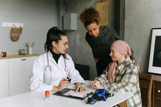 A person wearing a headscarf speaking to a doctor and support worker.