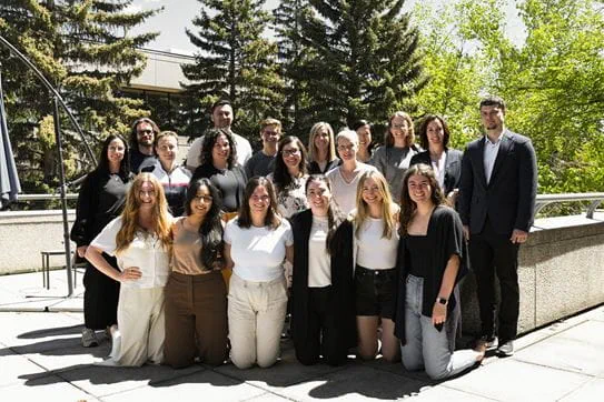 Dr Nicole Culos-Reed and her team are posing on an outdoor terrace with trees behind them
