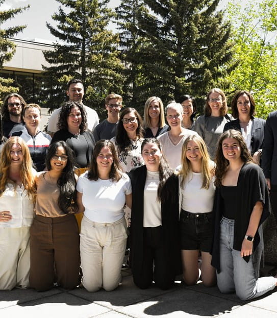Dr Nicole Culos-Reed and her team are posing on an outdoor terrace with trees behind them