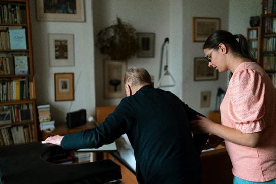 A person helping someone walk in their living room.