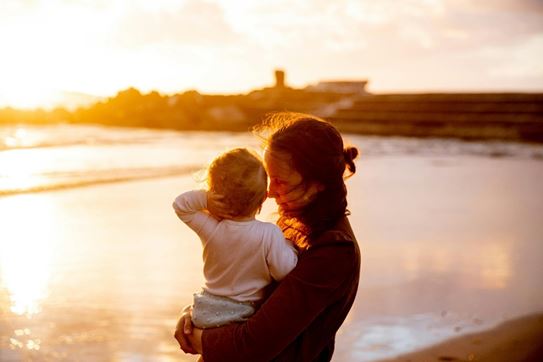 Une personne tenant un enfant sur une plage.